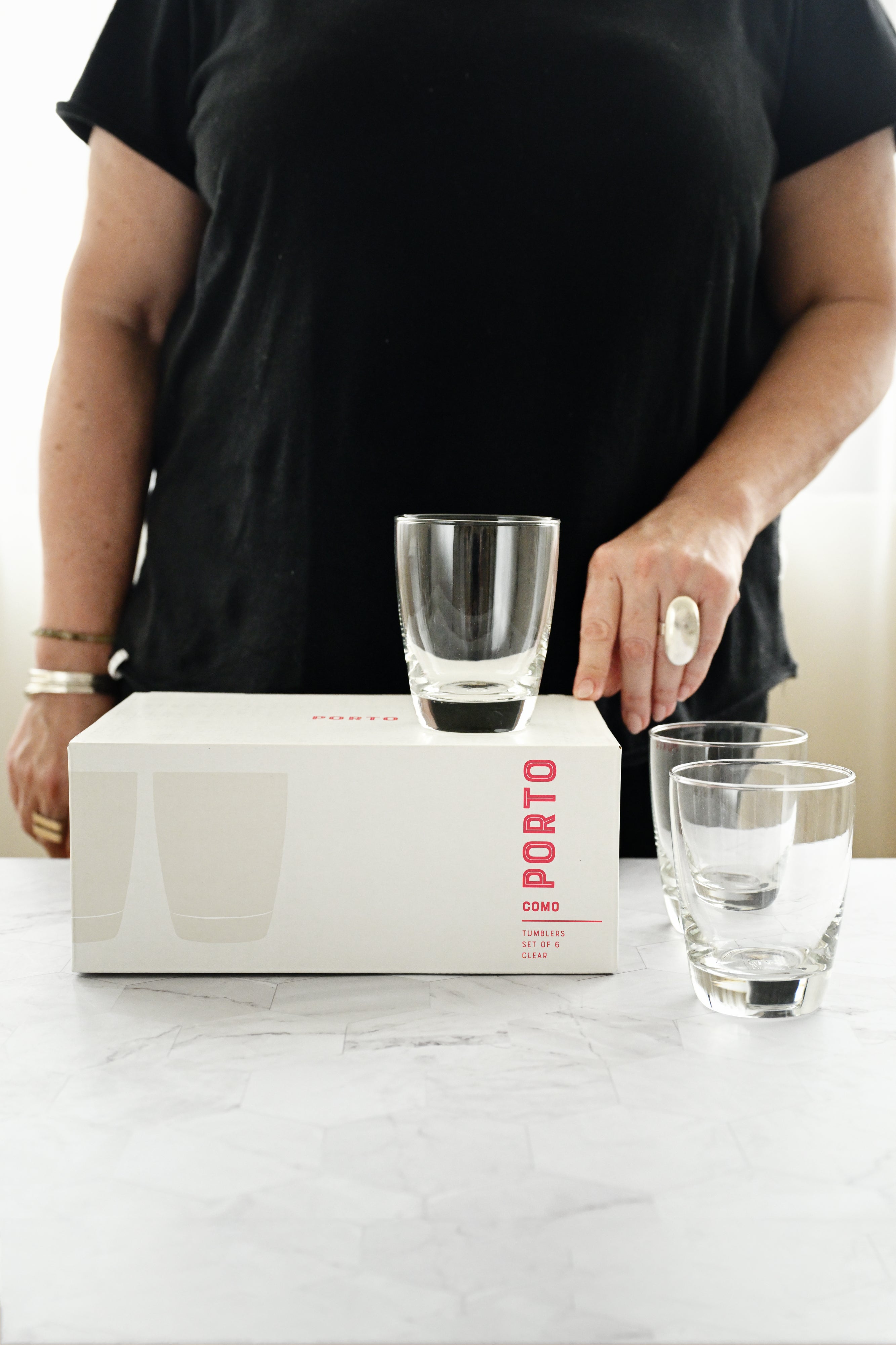 Person holding a glass above a Porto Cima wine box on a marble surface