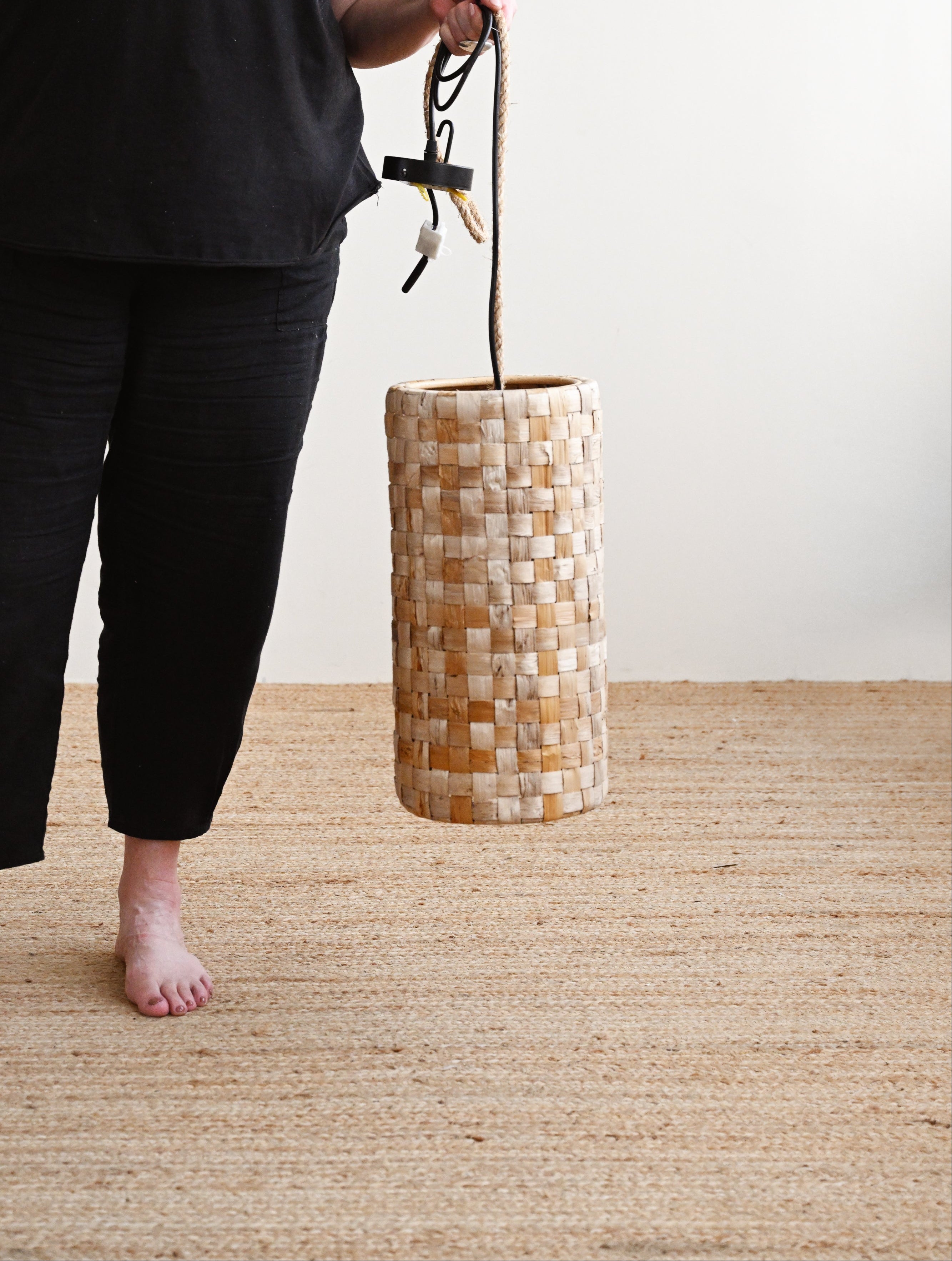 Person holding a woven basket on a wooden floor with a plain background