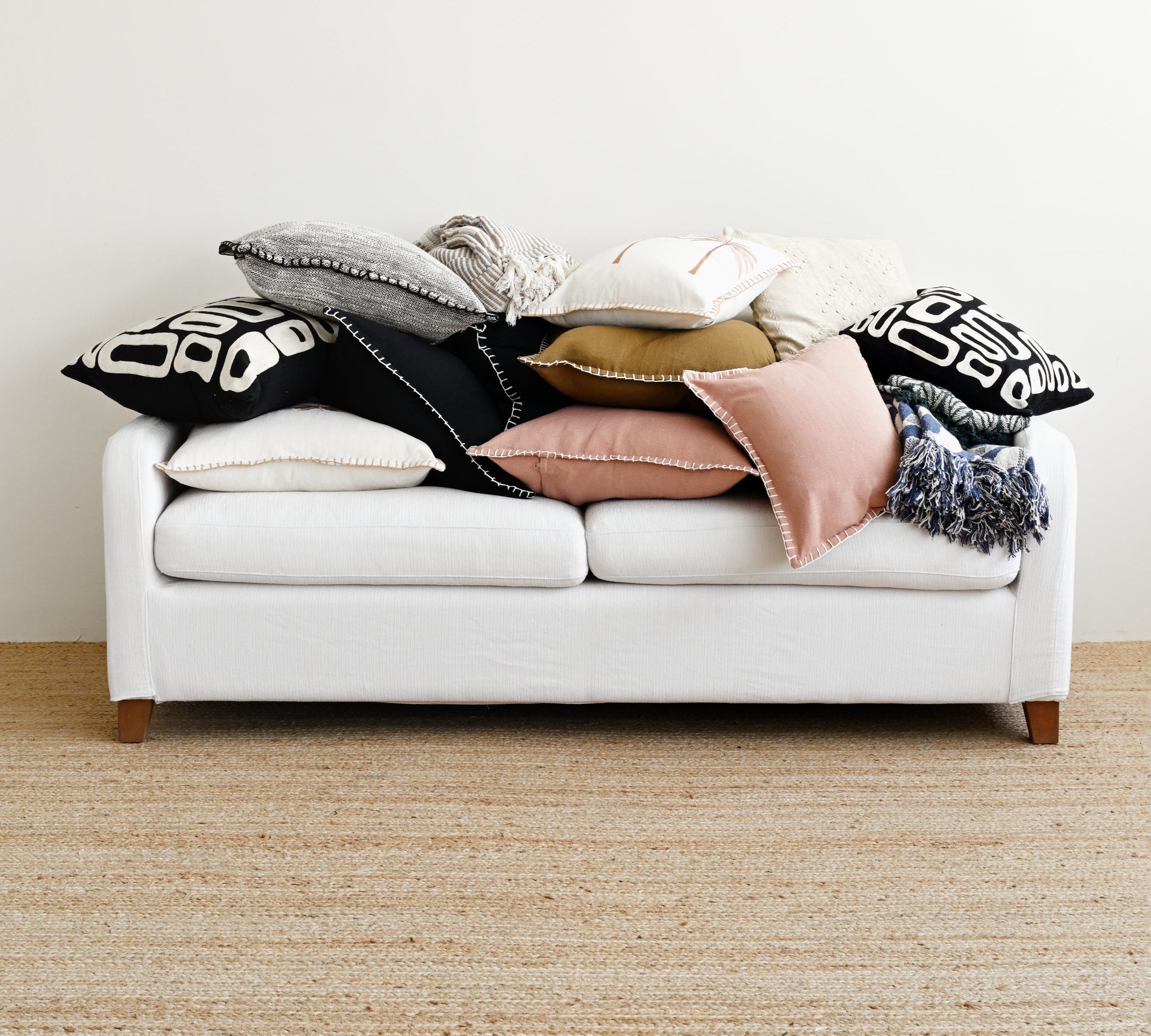 White sofa with a variety of pillows on a beige carpet