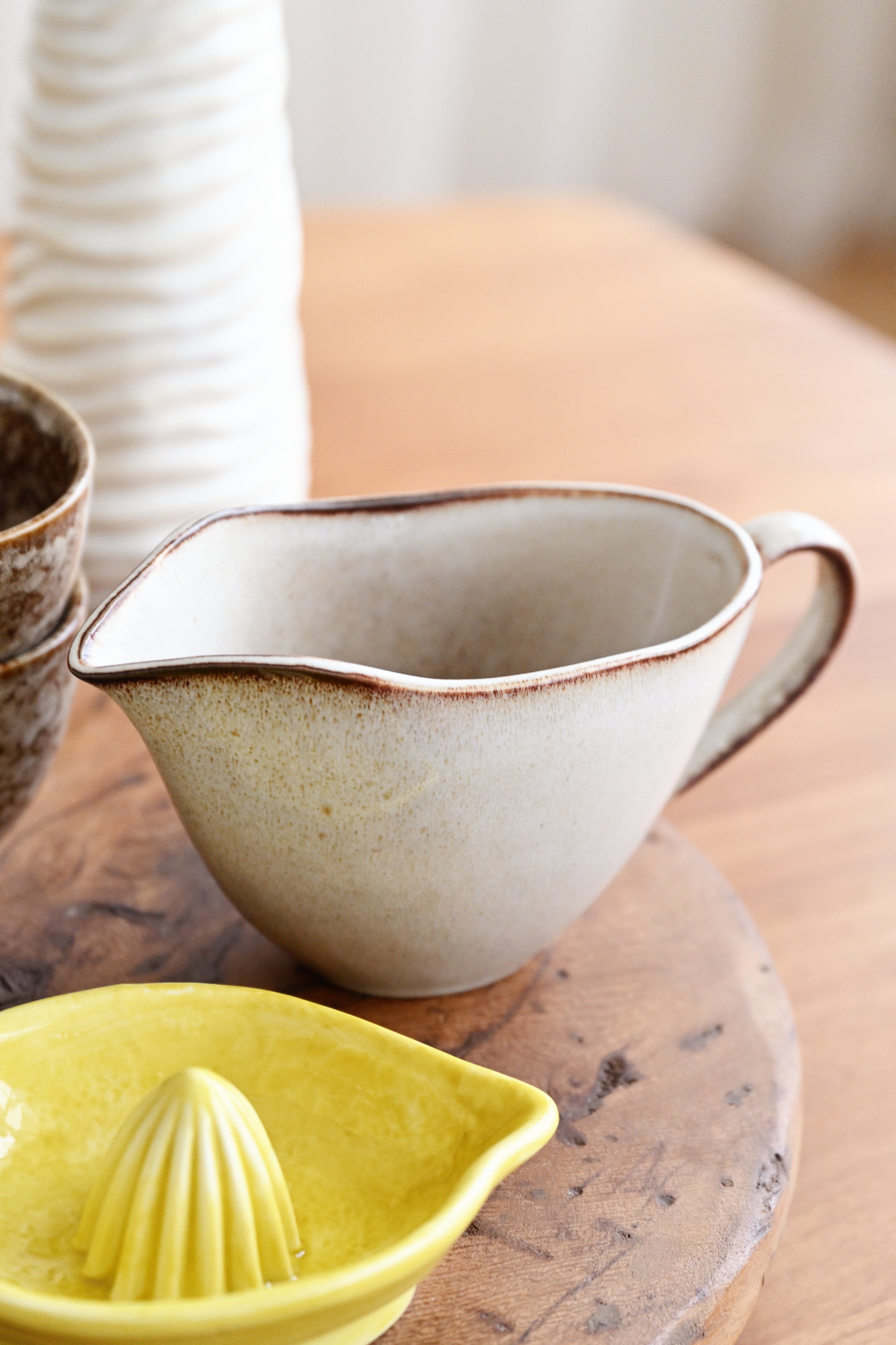 Ceramic pitcher and yellow citrus press on a wooden surface