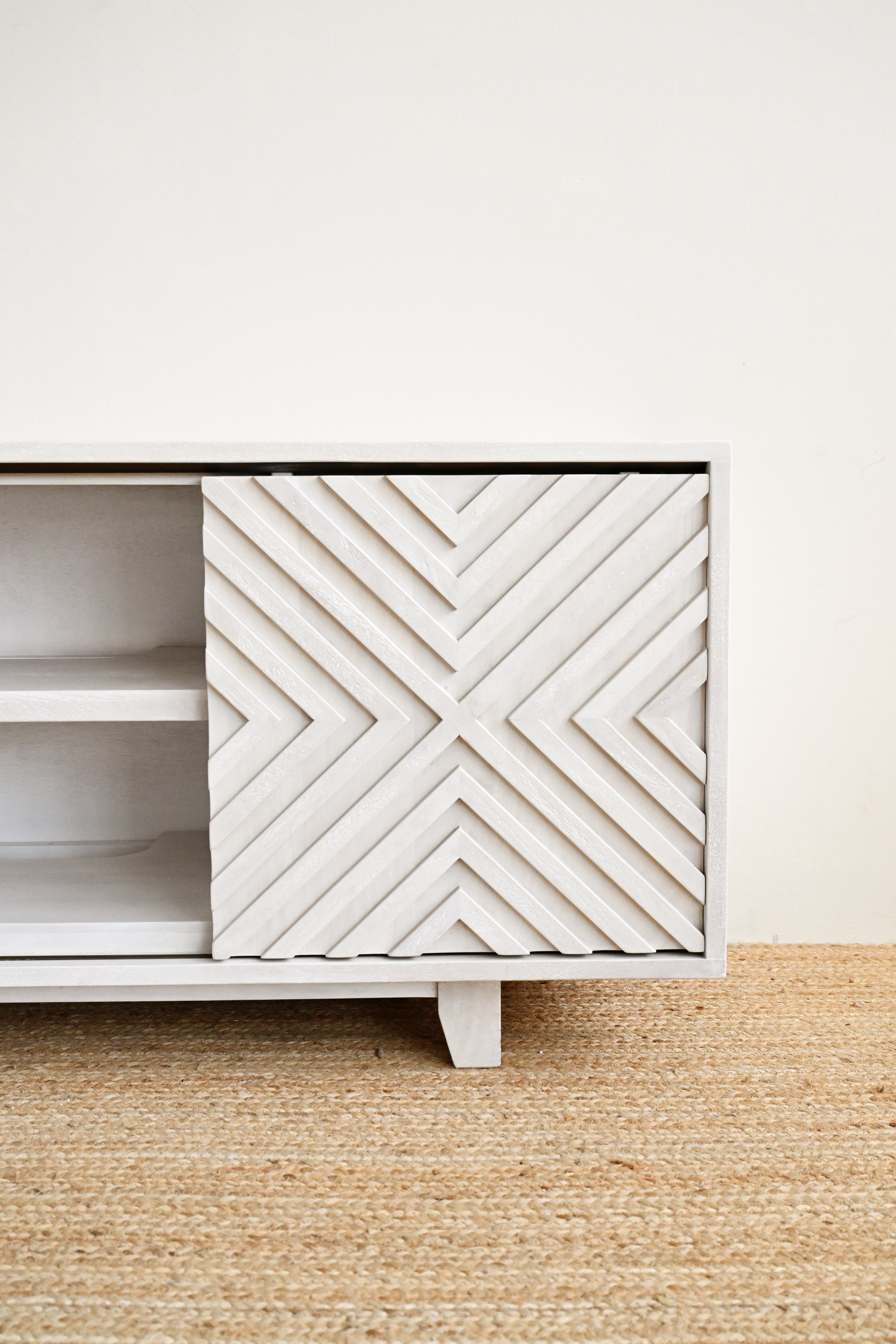 White cabinet with geometric pattern on a beige rug and white wall
