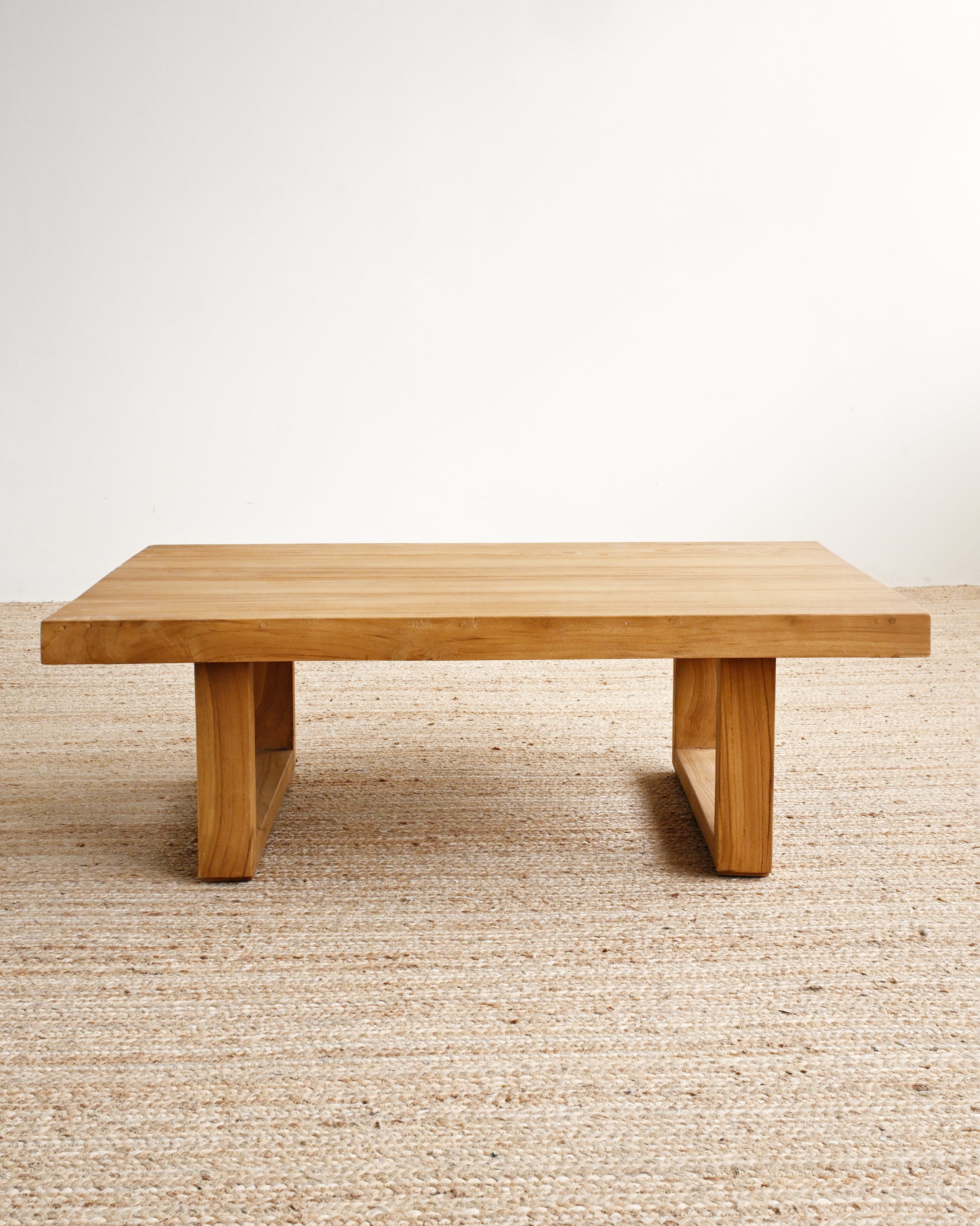 Wooden table on a beige carpet with a white wall background