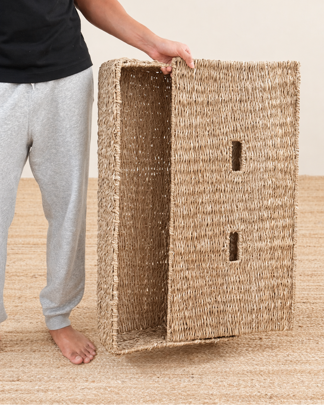 Person holding a woven seagrass box on a beige background