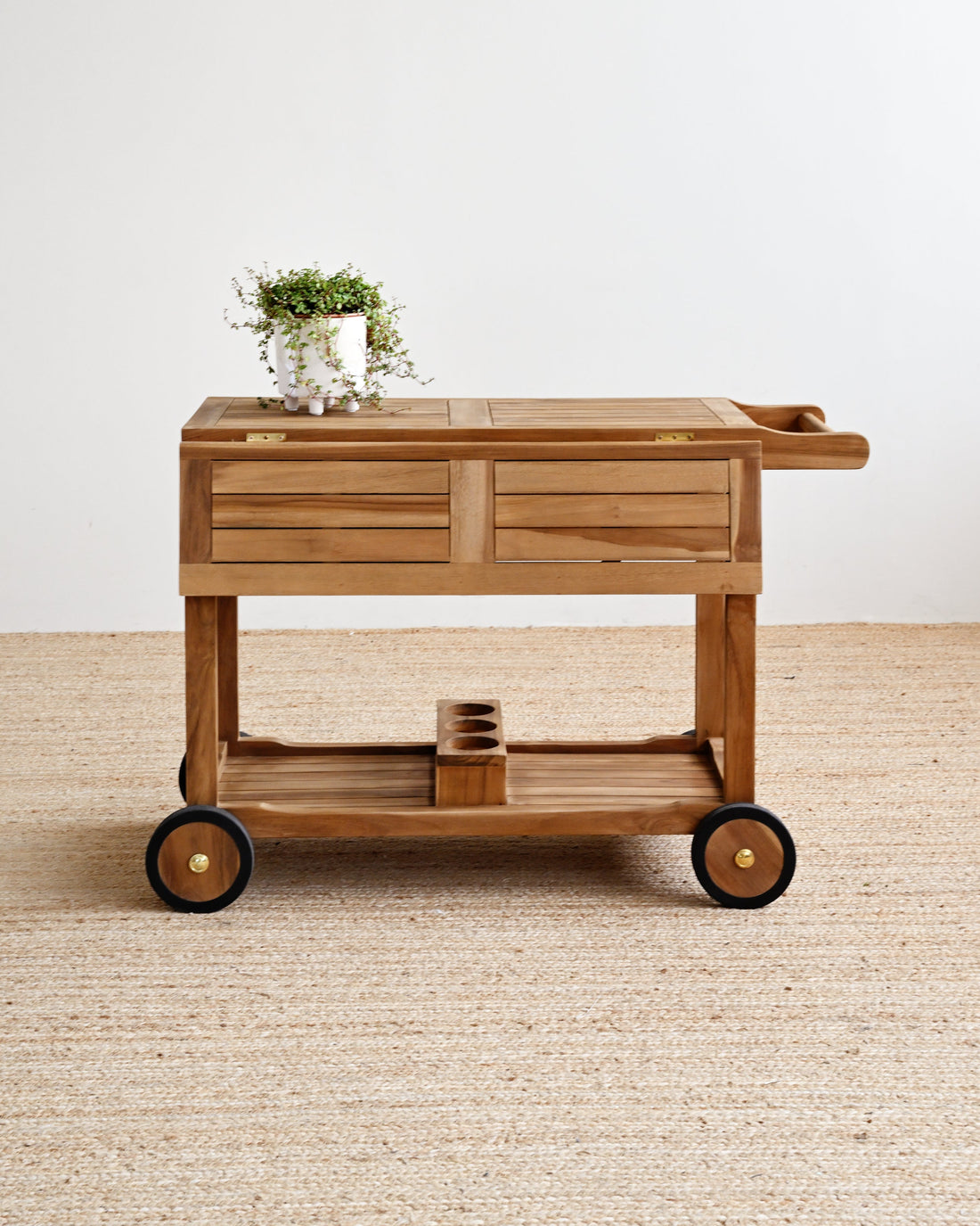 Teak serving cart with wheels on a beige carpet