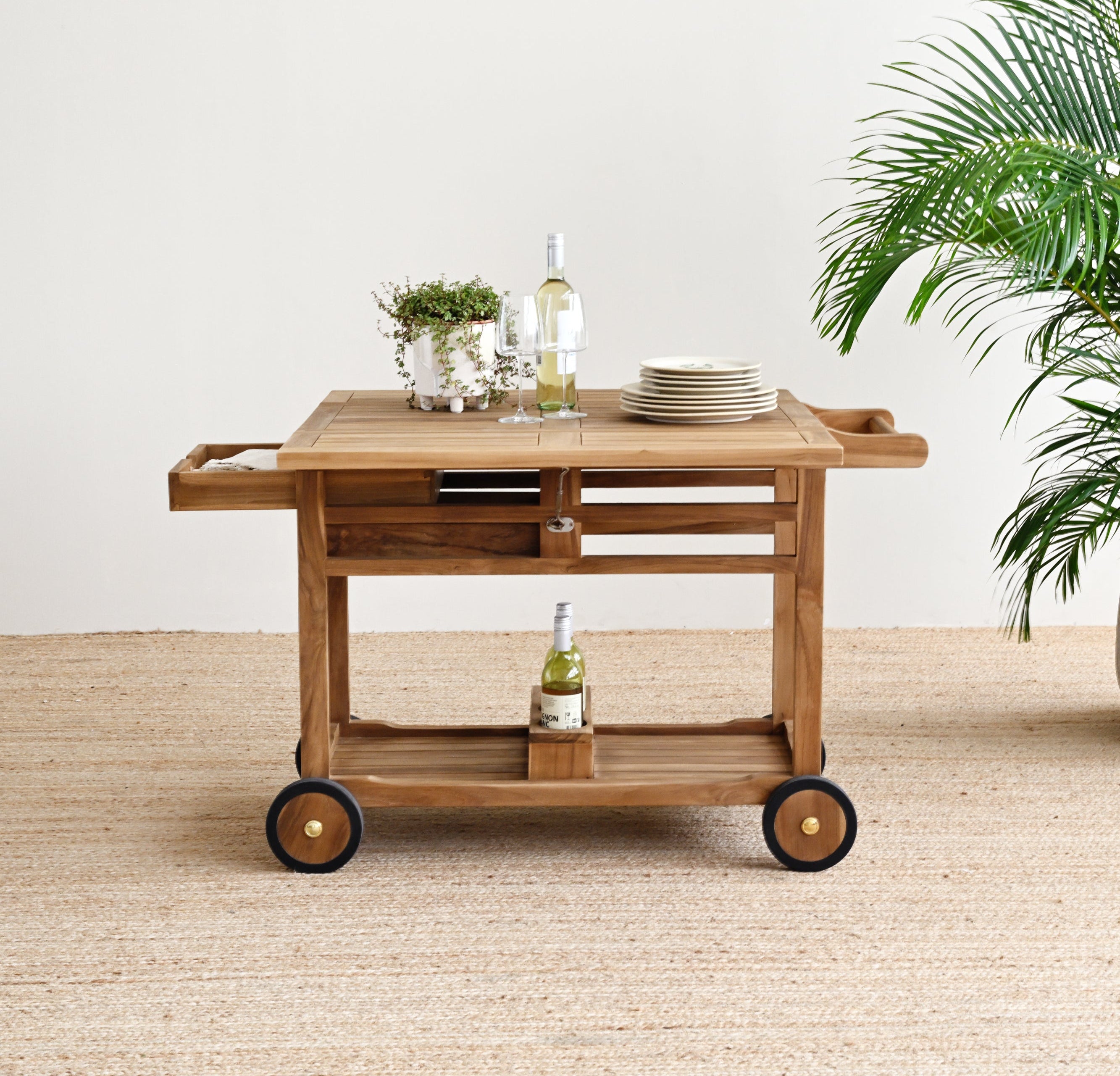 Wooden serving cart with bottles and plates on a beige carpeted floor.