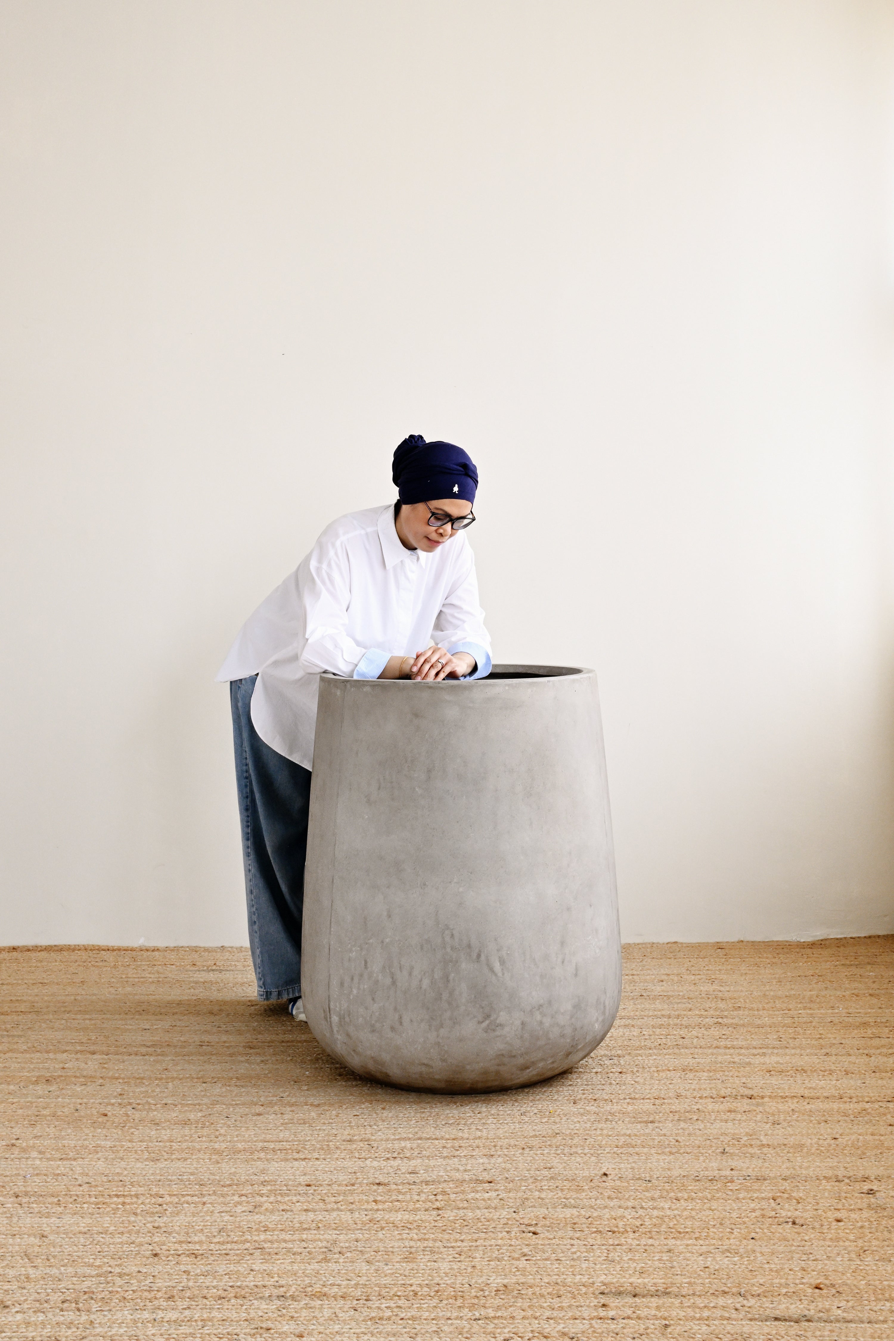 Person interacting with a large concrete planter in a minimalistic setting
