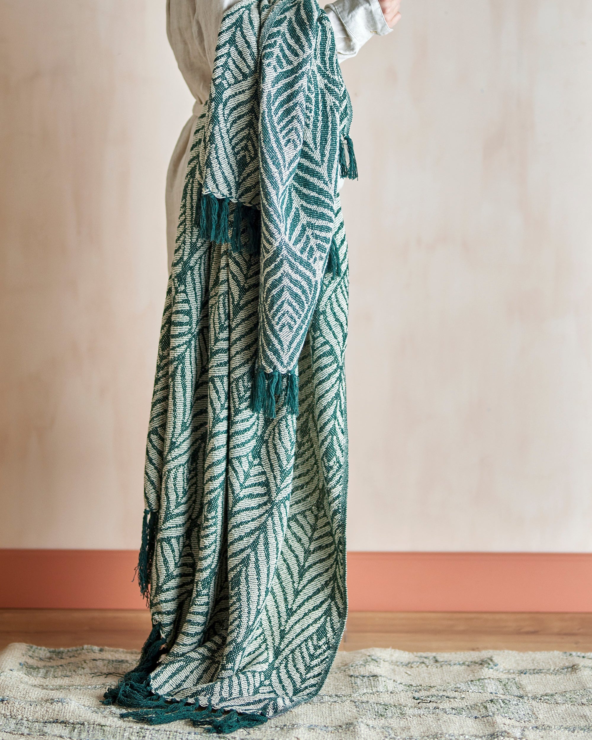 Person wearing a long, patterned green and white scarf against a plain background