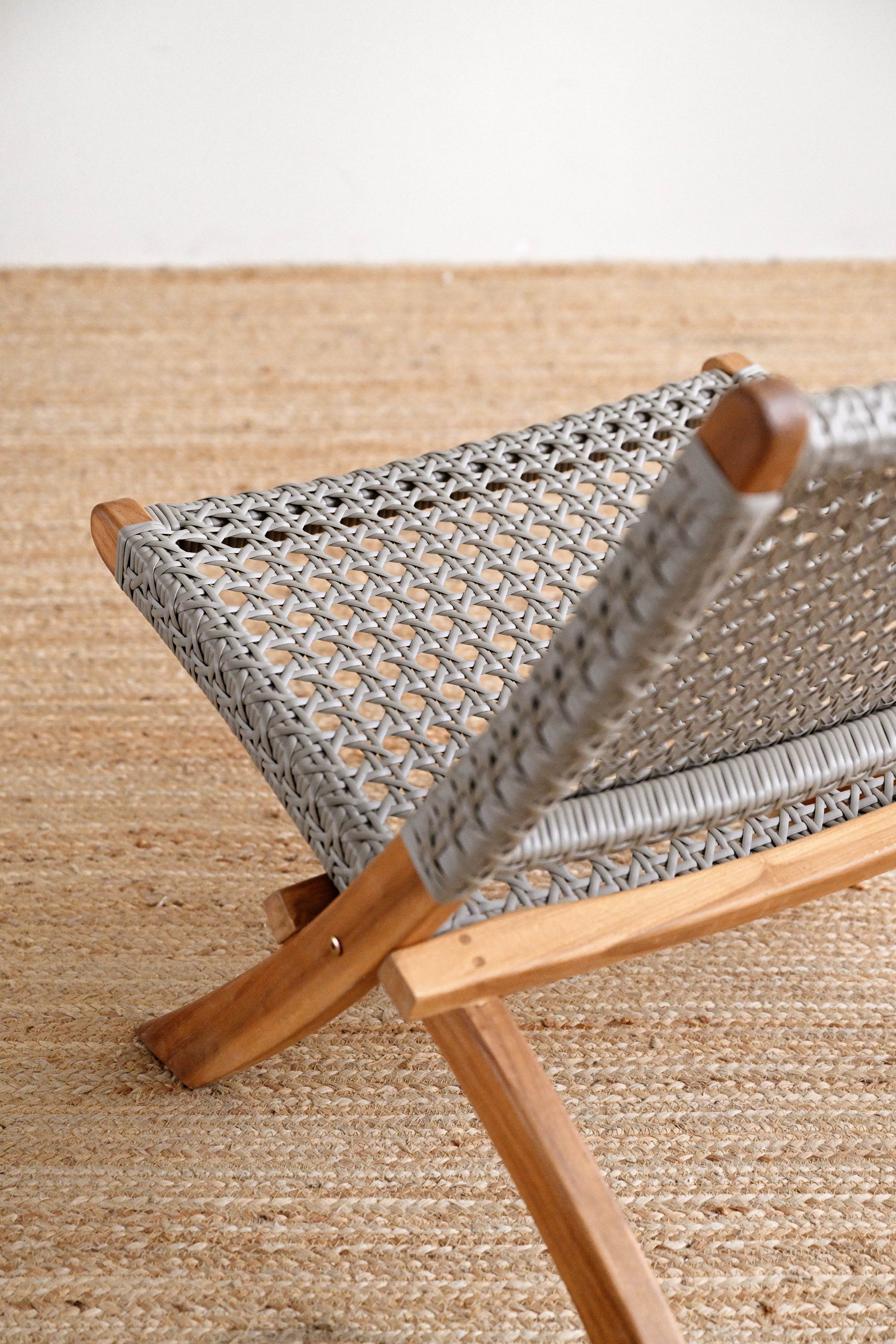 Close-up of a woven chair with wooden frame on a textured surface