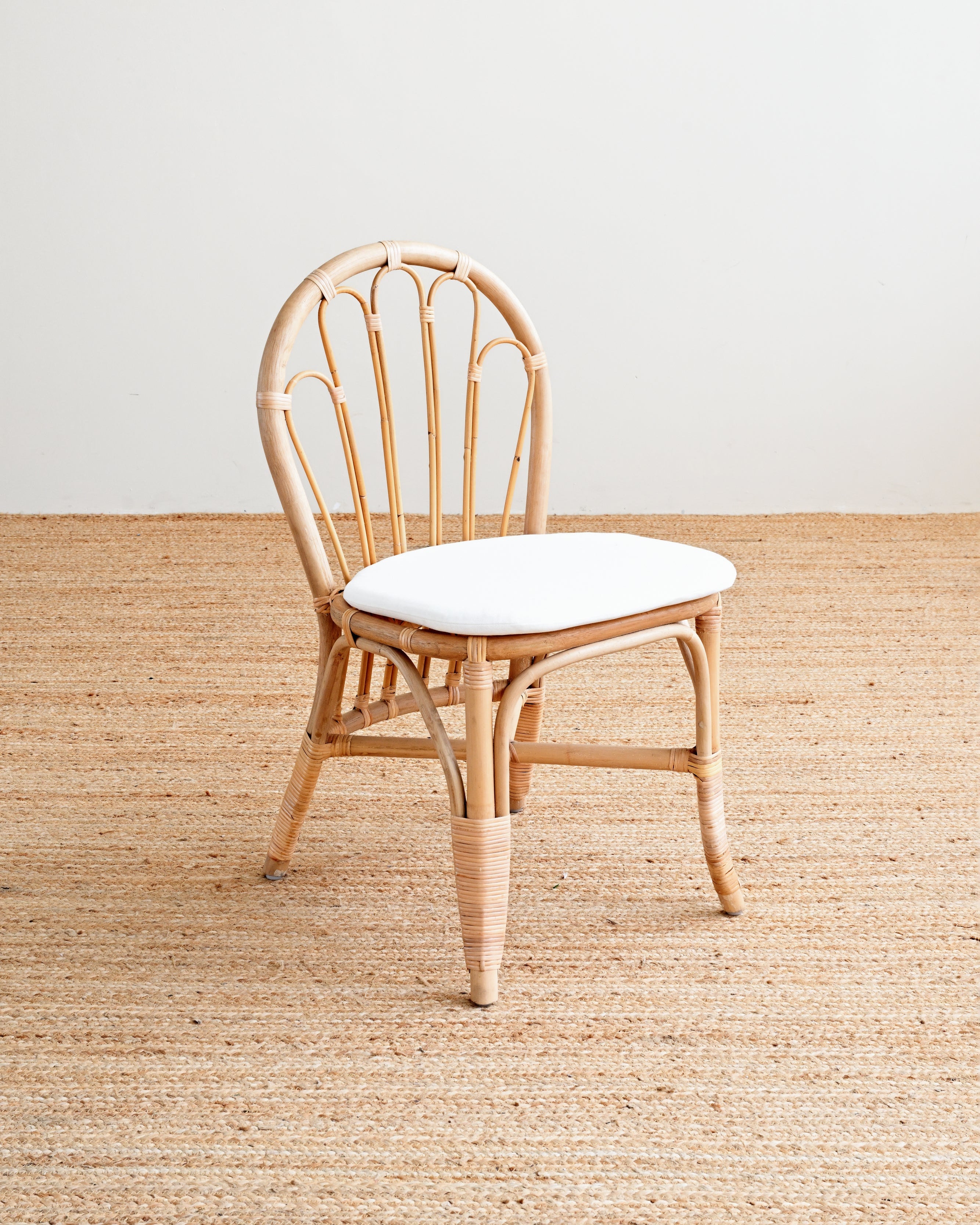Wooden chair with a white cushion on a wooden floor.