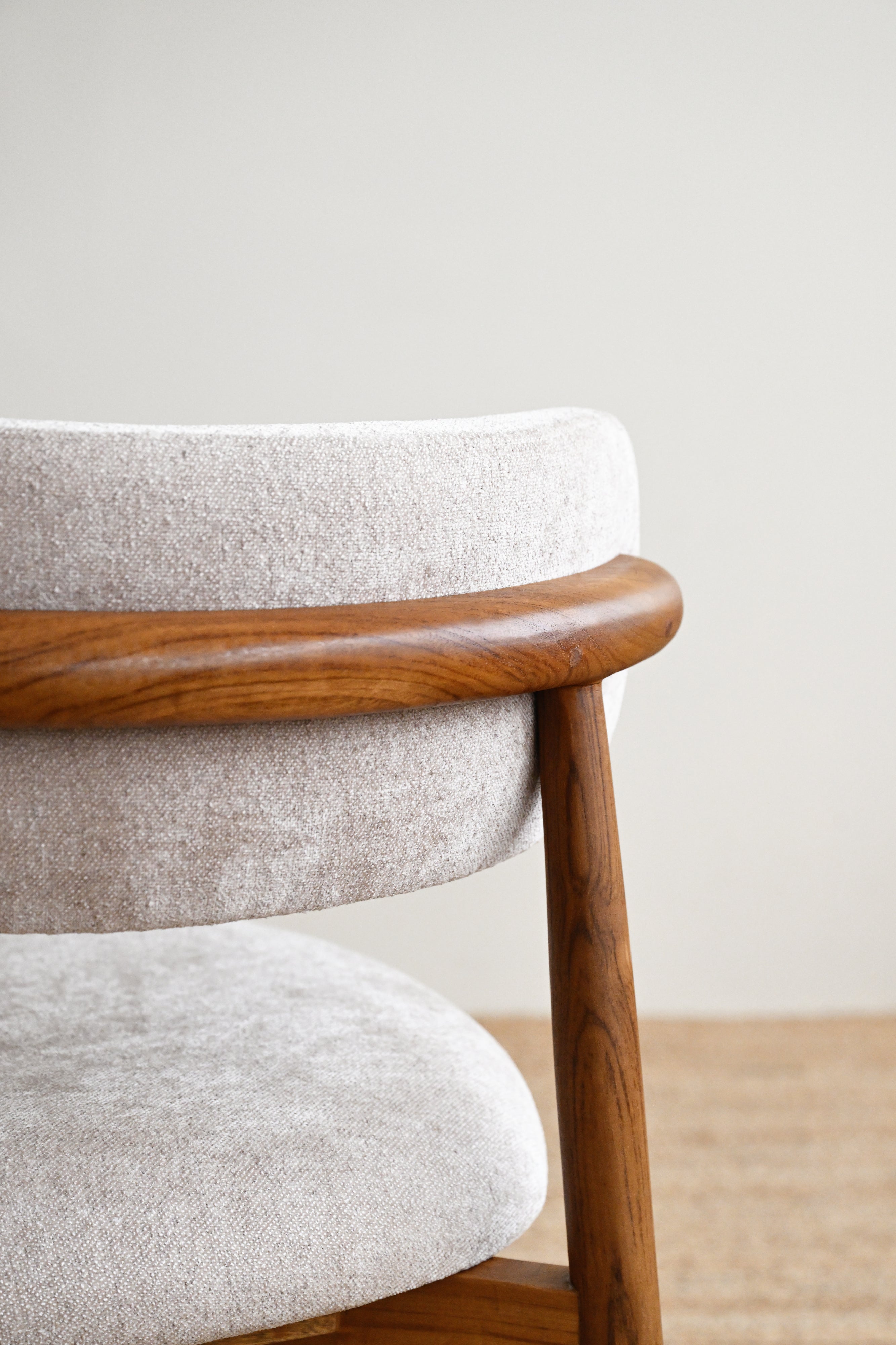Close-up of a chair with wooden armrest and legs against a plain background