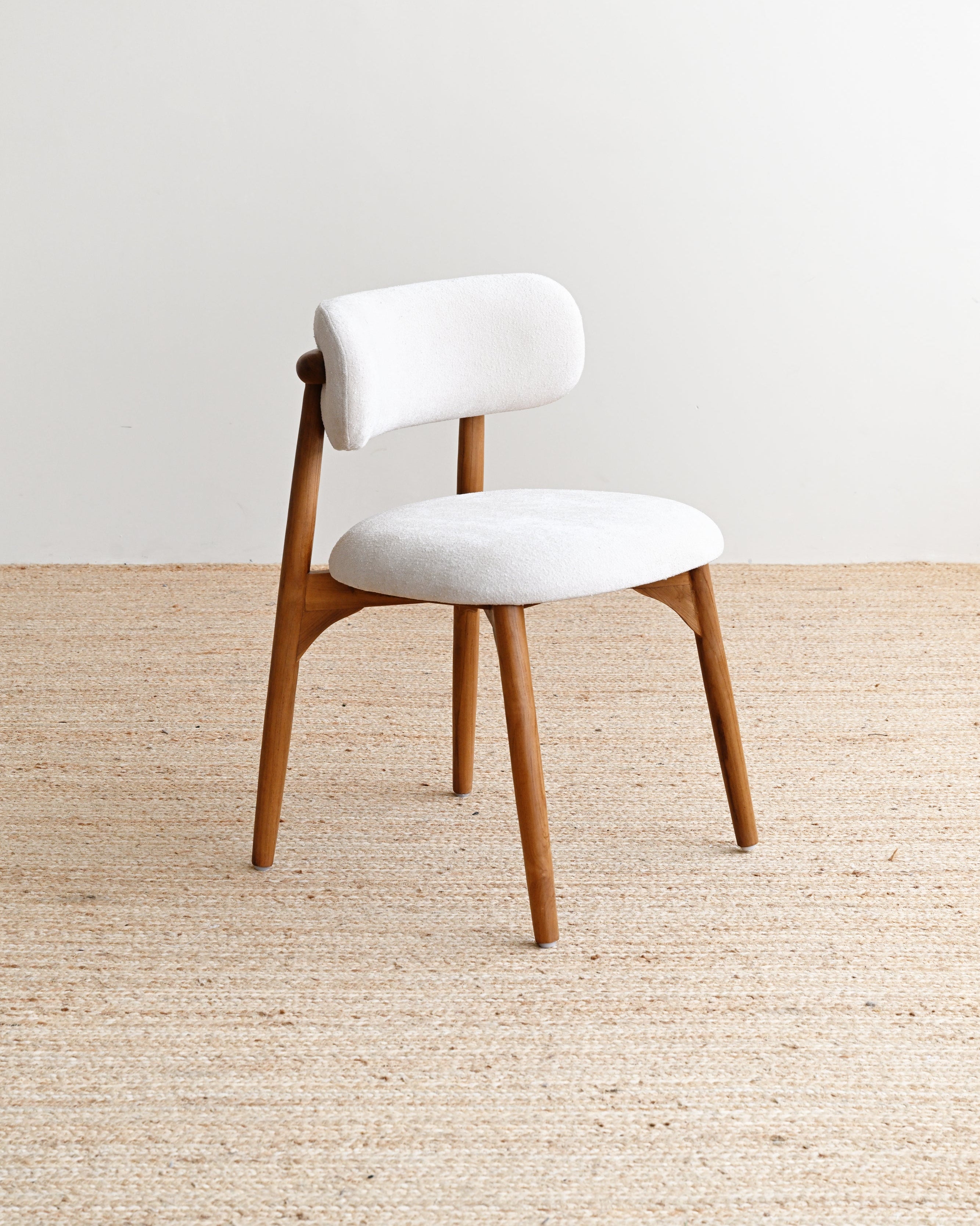 White cushioned chair with wooden legs on a beige carpet