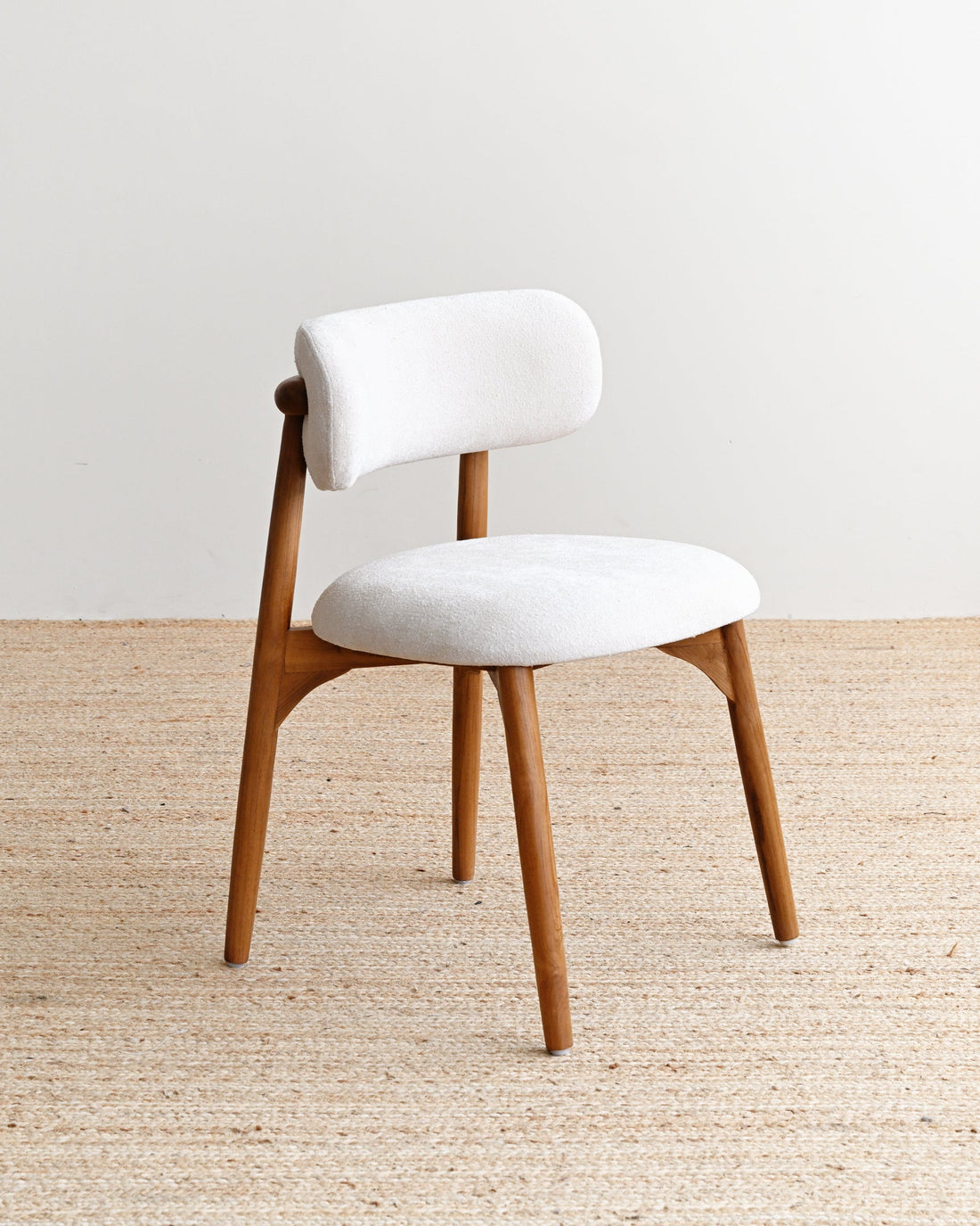 White cushioned chair with wooden legs on a beige carpet