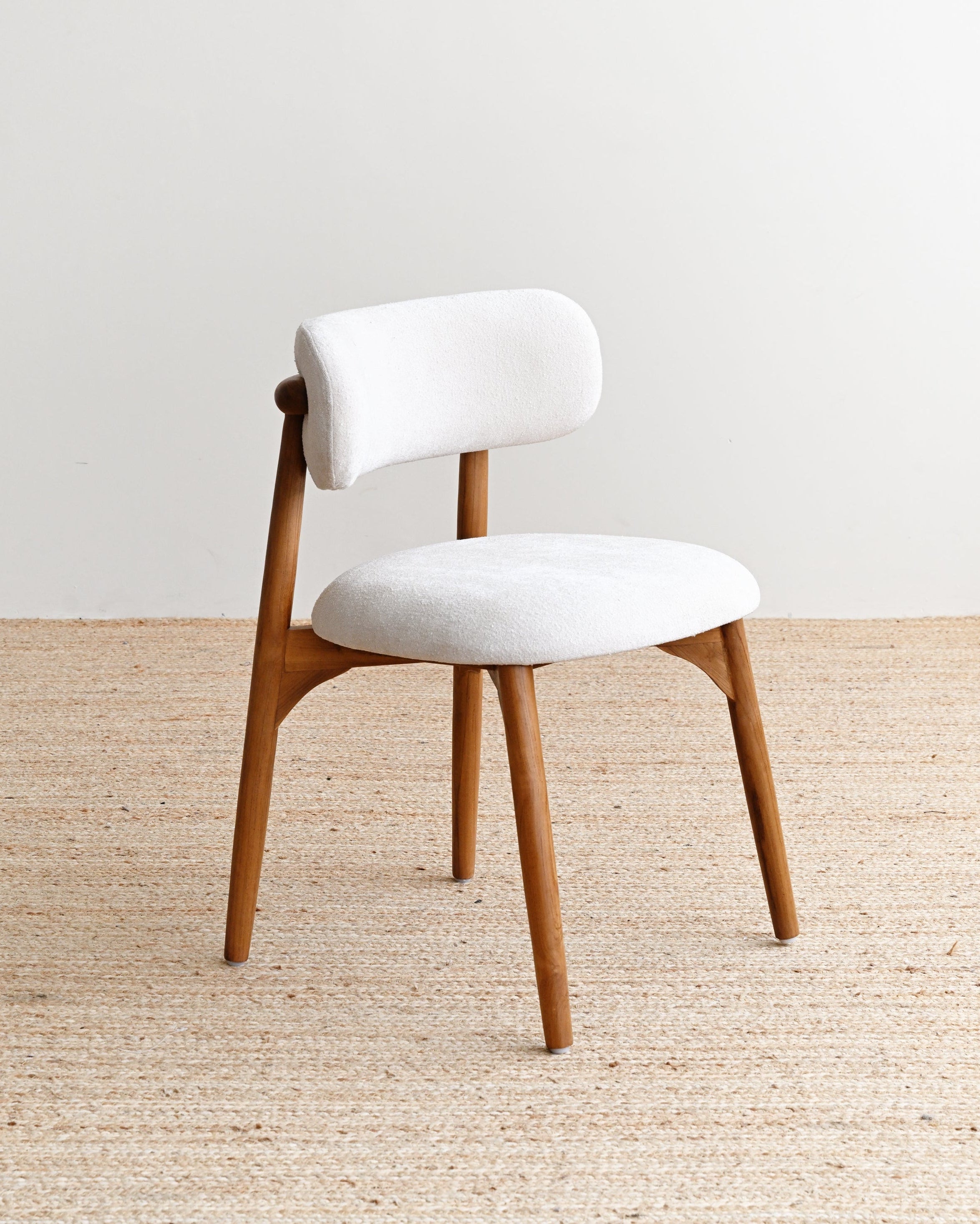 White cushioned chair with wooden legs on a beige carpet