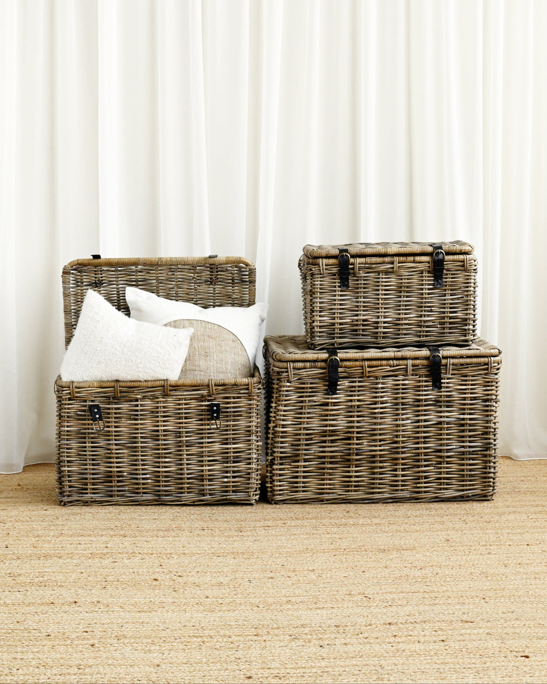 Set of wicker storage baskets with pillows against a white curtain background