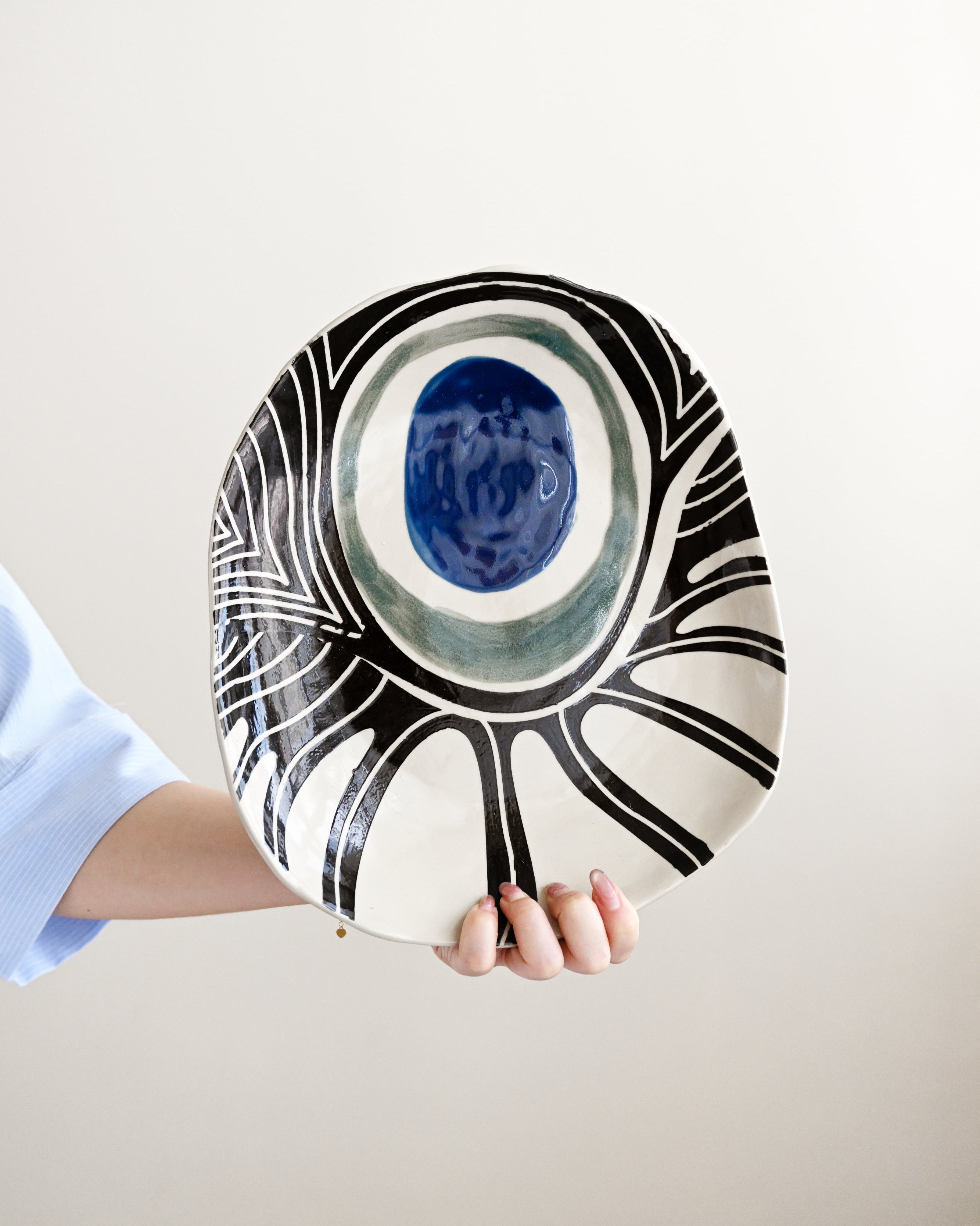 Ceramic plate with black and white abstract design held by a person on a light background