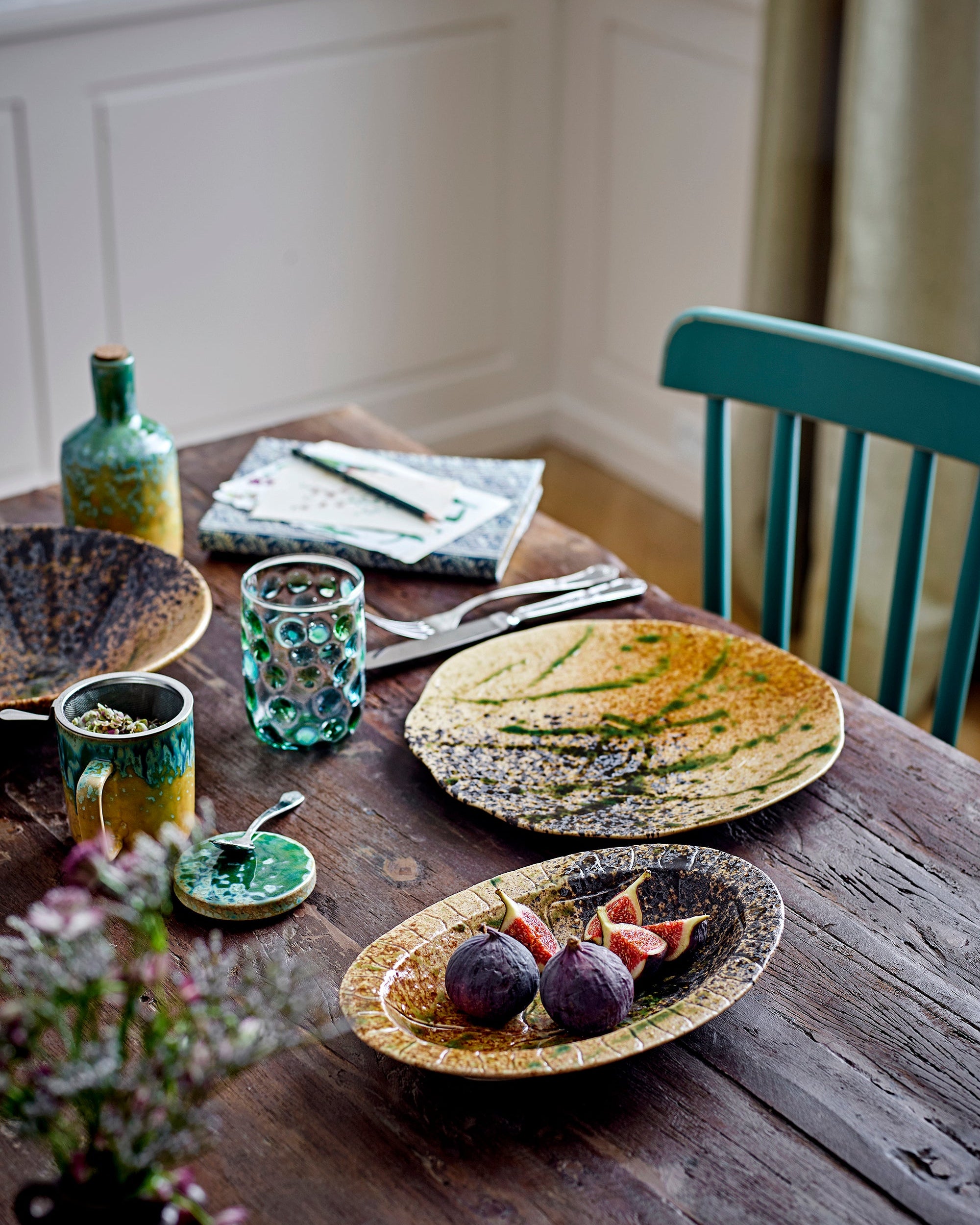 Dining table with ceramic plates, glasses, and cutlery in a home setting.