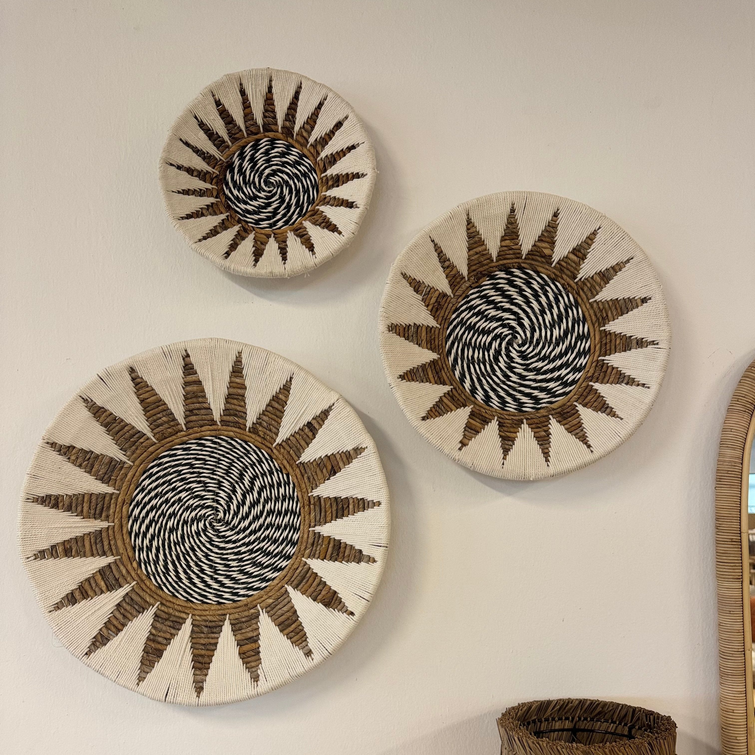 A set of three wall deco items made of natural and white fibers with a geometric pattern, handmade in Indonesia, displayed on a wall.