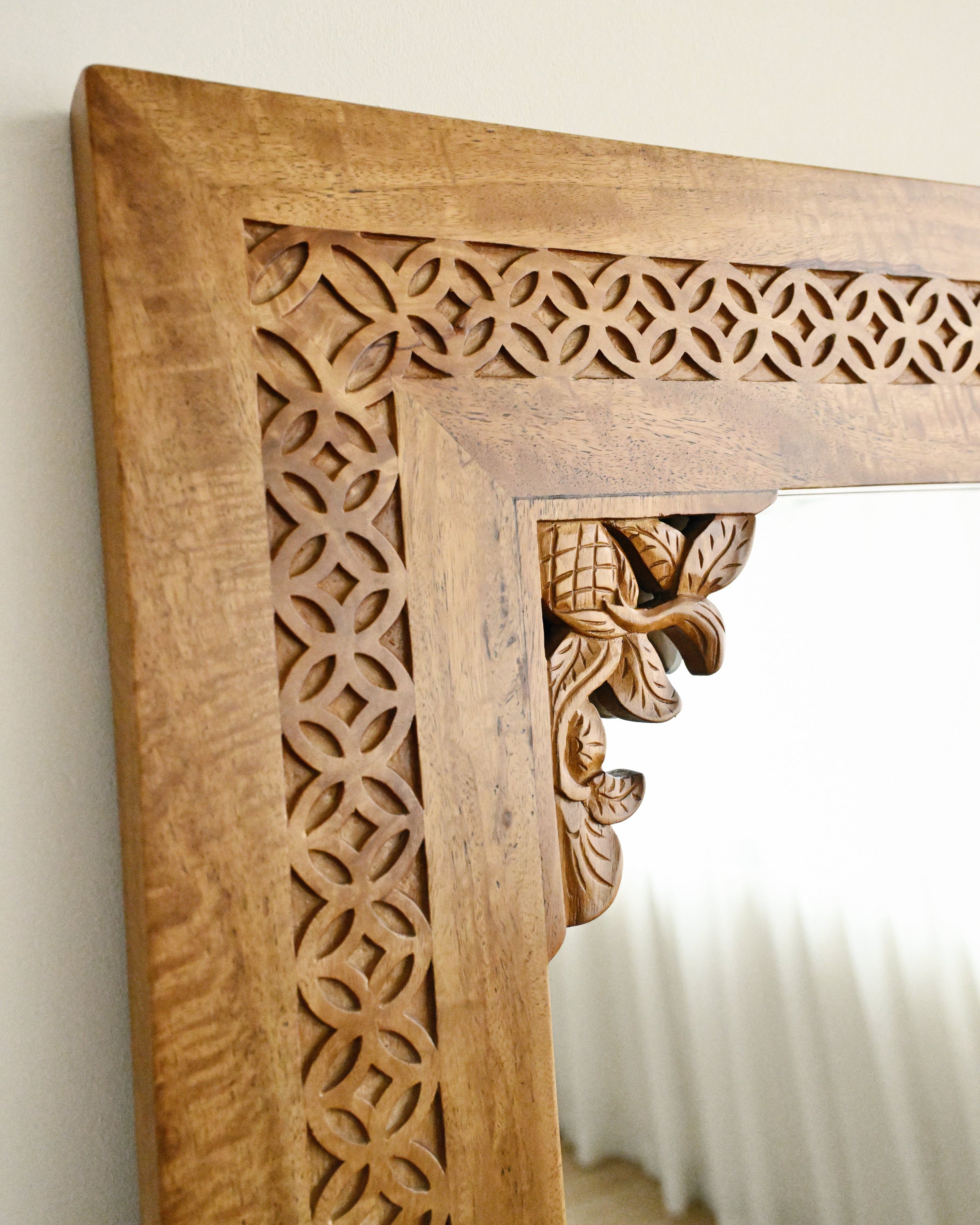 Wooden mirror frame with intricate carvings on a white wall