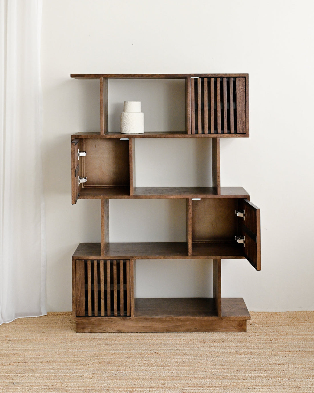Wooden bookshelf with open doors against a white wall