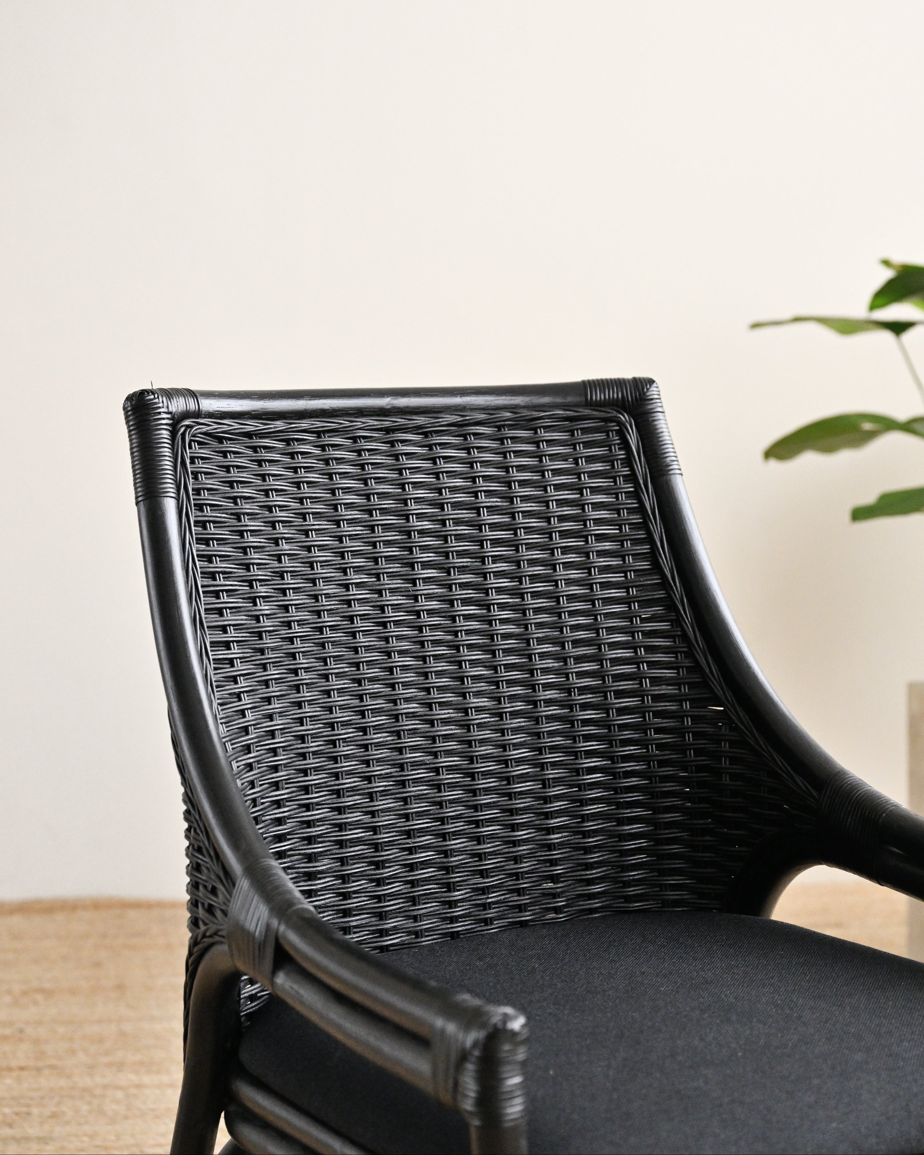 Black wicker chair with a cushioned seat against a light background