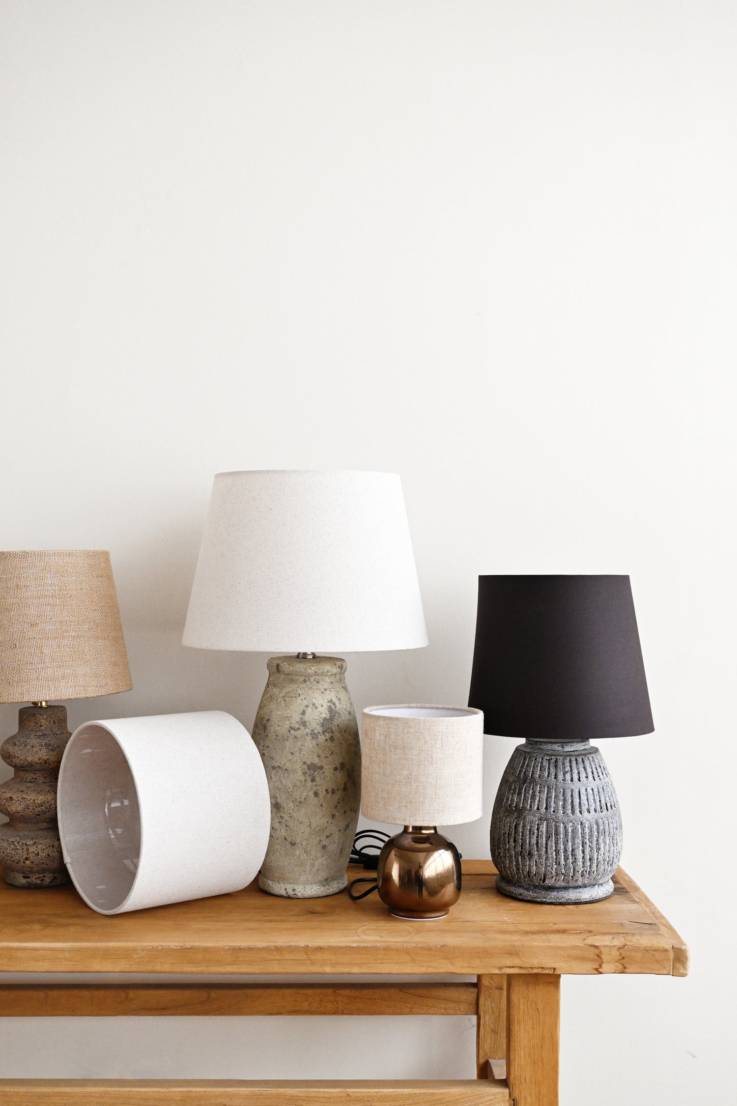 Collection of various lamps on a wooden surface with a white wall background