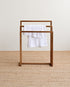 Wooden towel rack with a white towel on a beige carpet and light-colored wall background