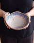 Person holding a ceramic bowl with a textured surface