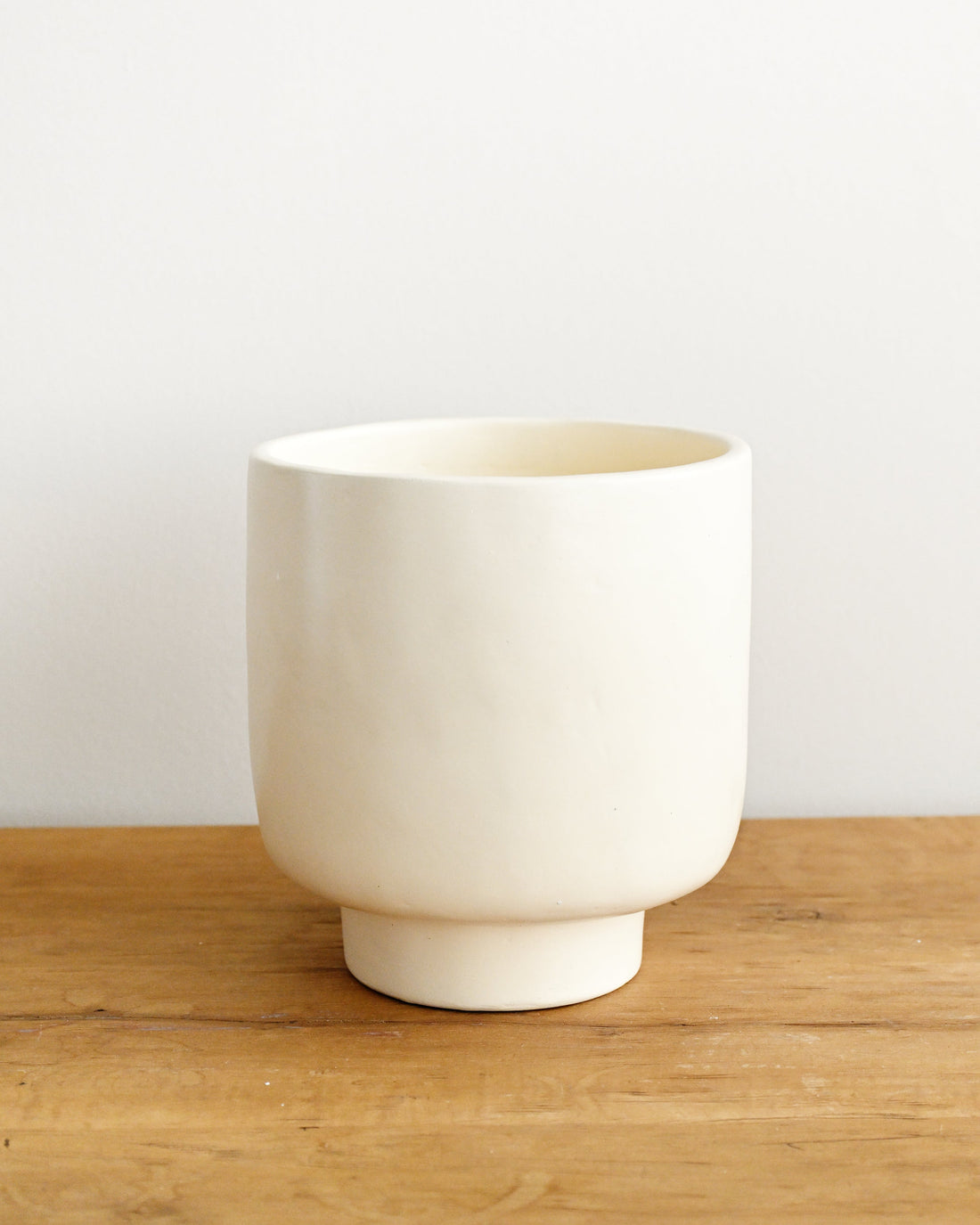 White ceramic cup on a wooden surface with a plain background
