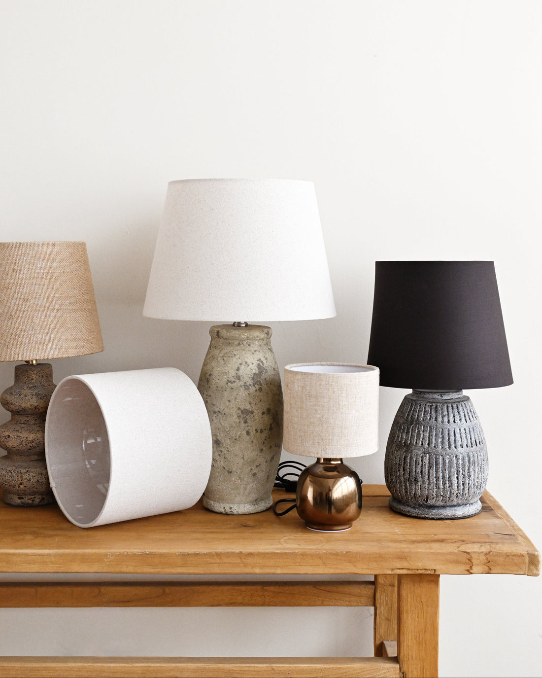 Collection of various lamps on a wooden surface with a white wall background