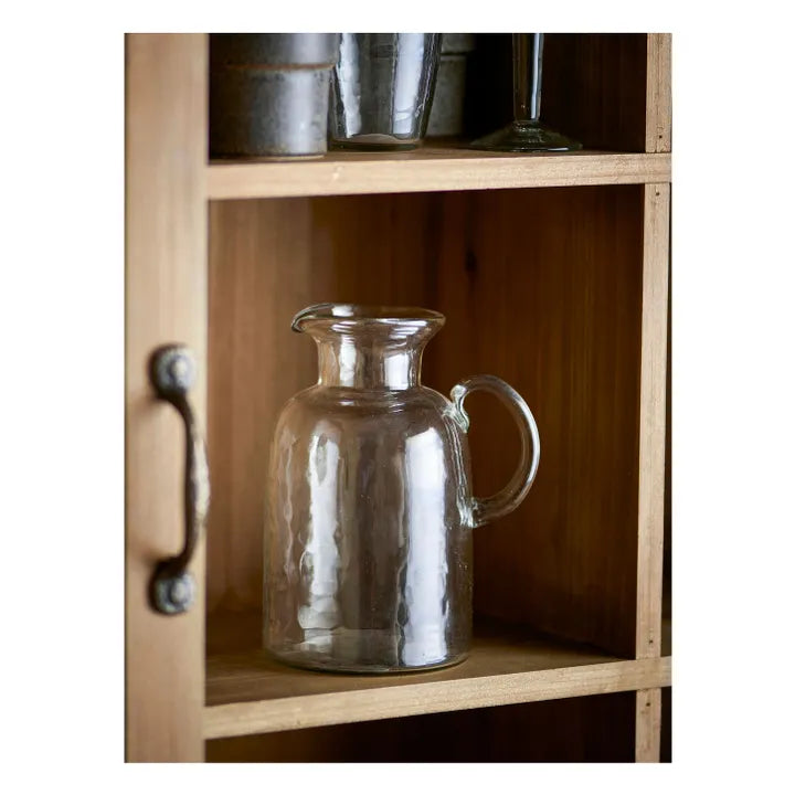 Clear glass carafe on a wooden shelf with metal containers.
