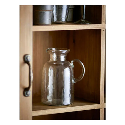 Clear glass carafe on a wooden shelf with metal containers.