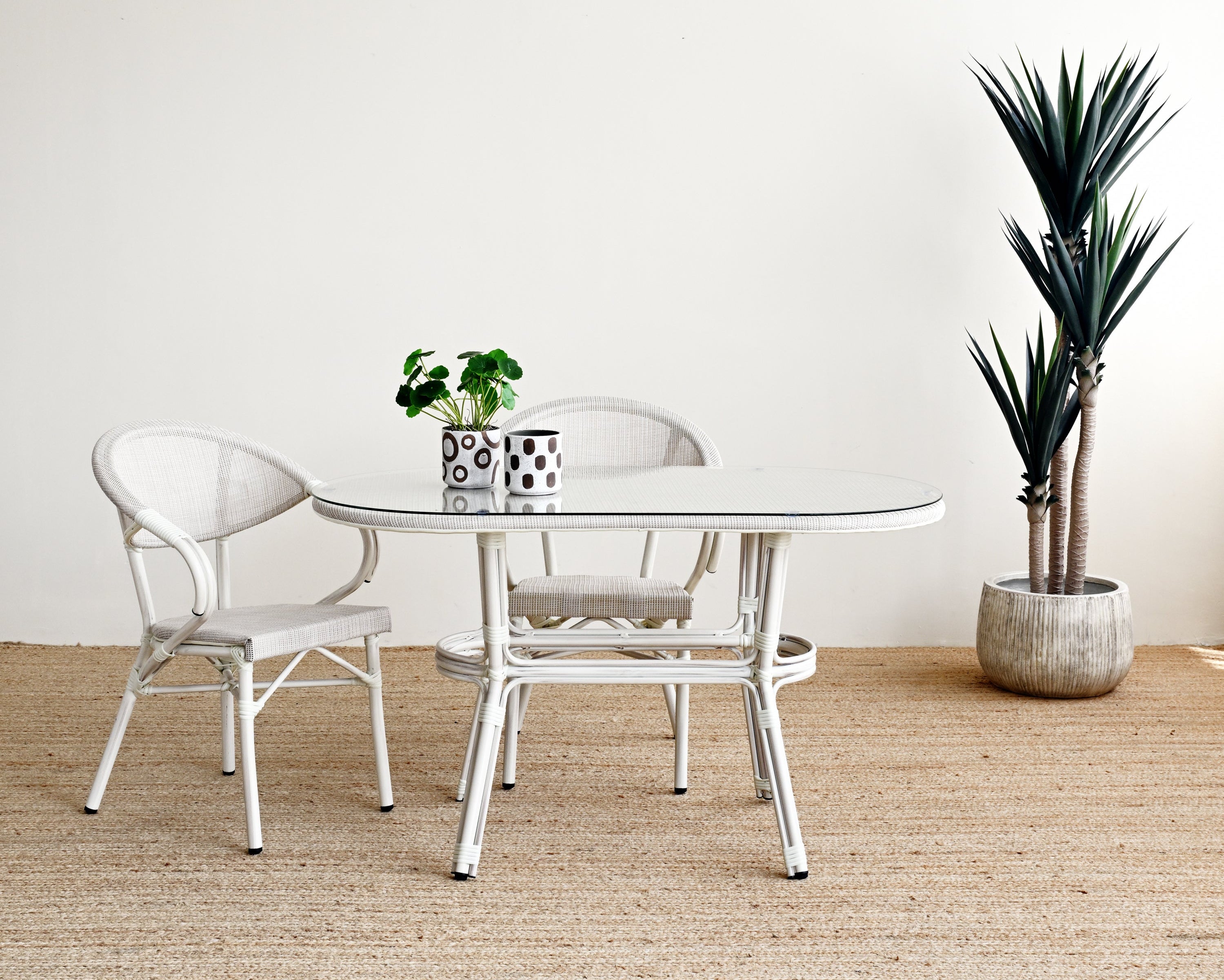 Dining area with a round glass table and two chairs on a textured beige floor.