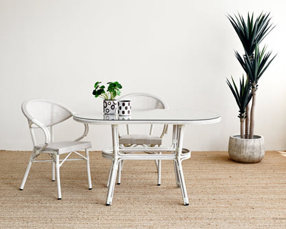 Dining area with a round glass table and two chairs on a textured beige floor.