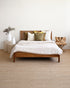 Wooden bed with white bedding in a minimalistic room