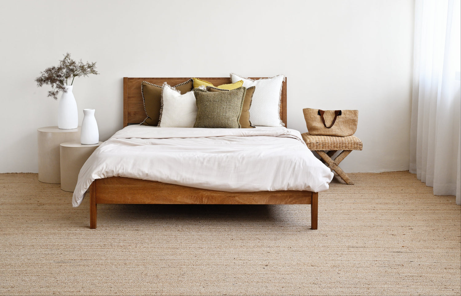 Wooden bed with white bedding and pillows in a minimalistic bedroom.
