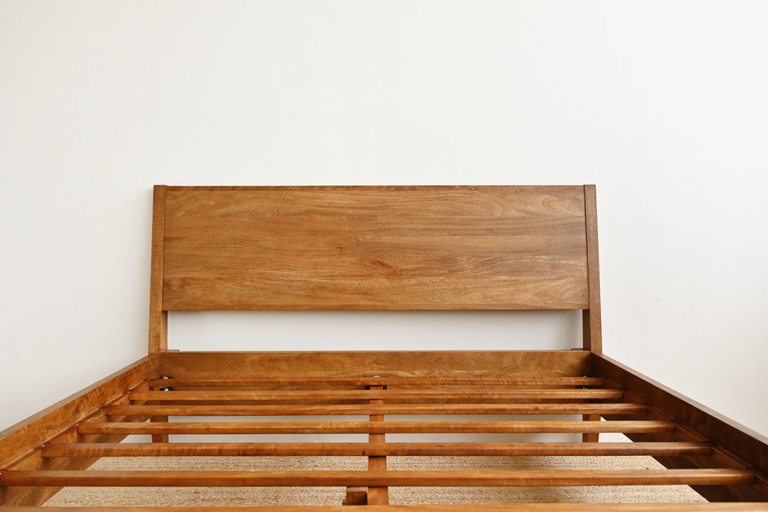 Wooden bed frame against a white wall