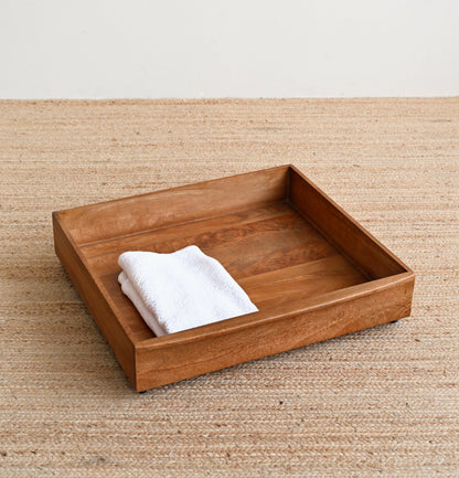 Wooden tray with a white towel on a beige surface