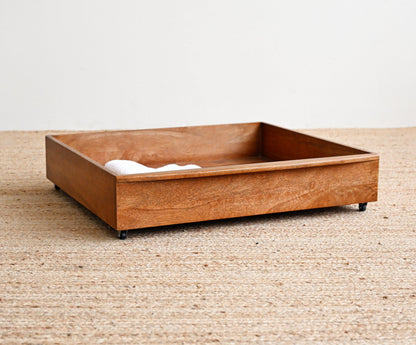 Wooden pet bed on a textured beige floor with a white wall background