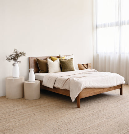 Bedroom with a wooden bed, beige bedding, and side tables.