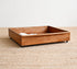 Wooden pet bed on a textured beige floor with a white wall background