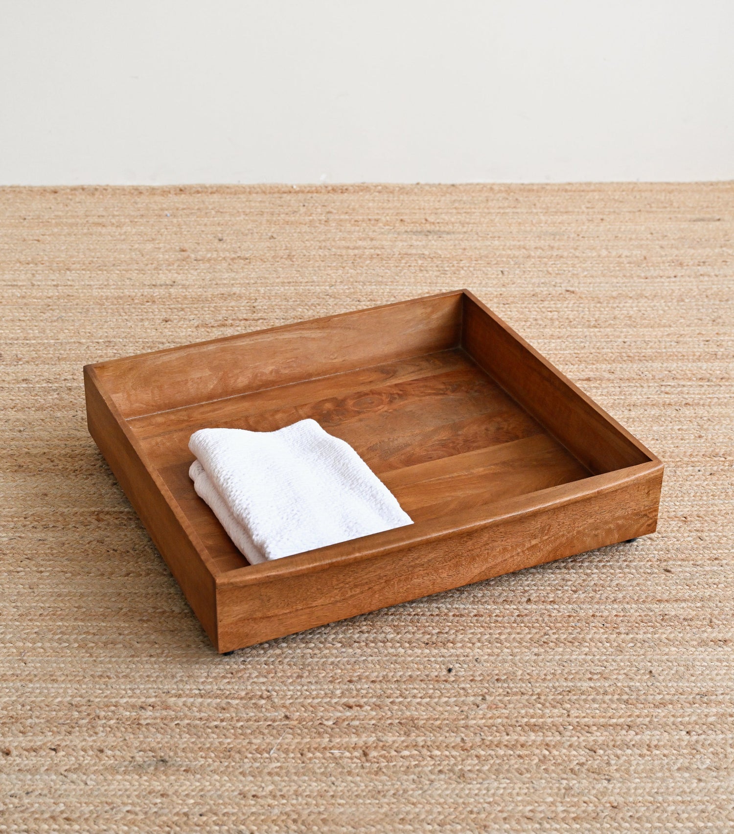 Wooden tray with a white towel on a beige surface