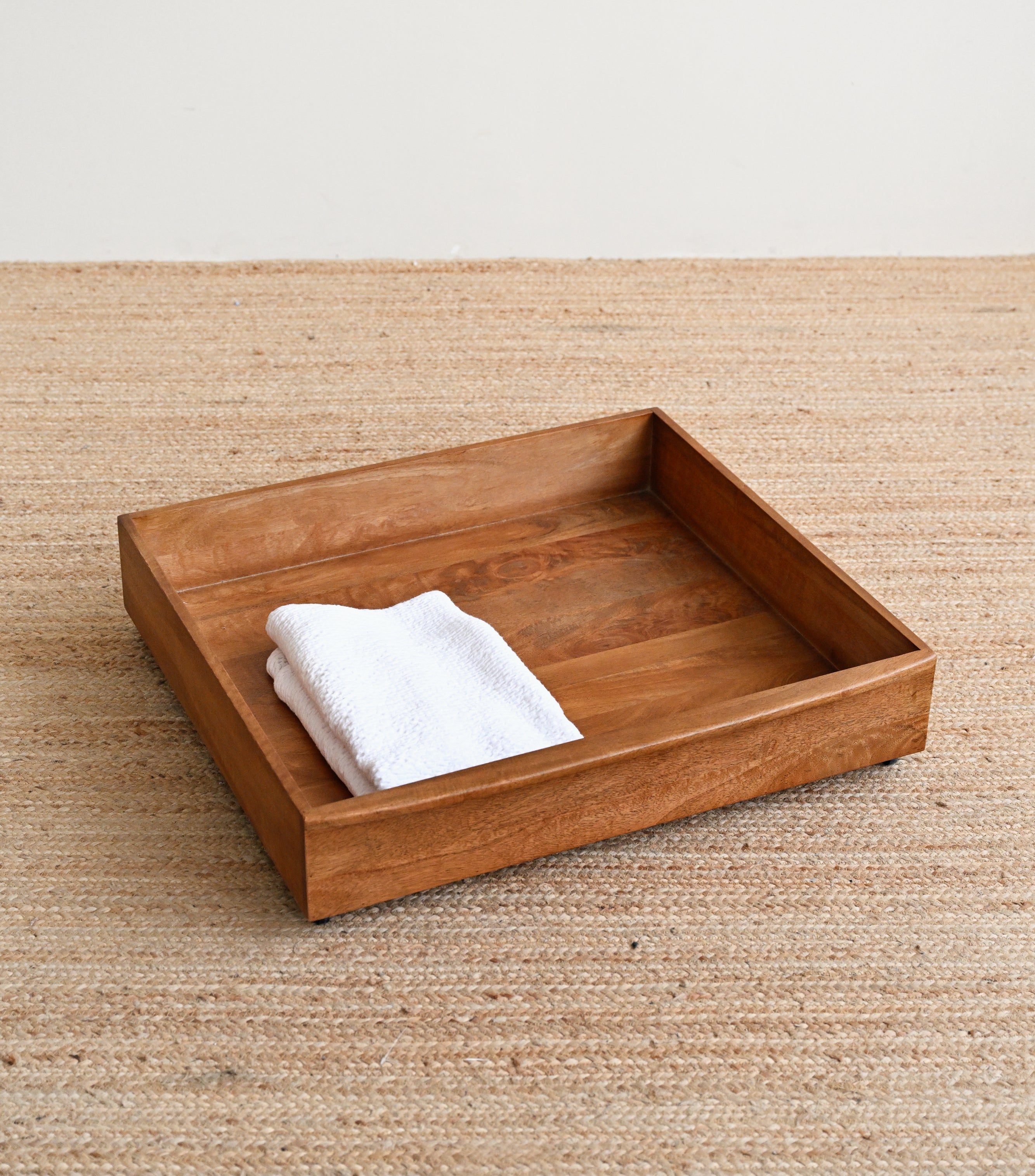 Wooden tray with a white towel on a beige surface