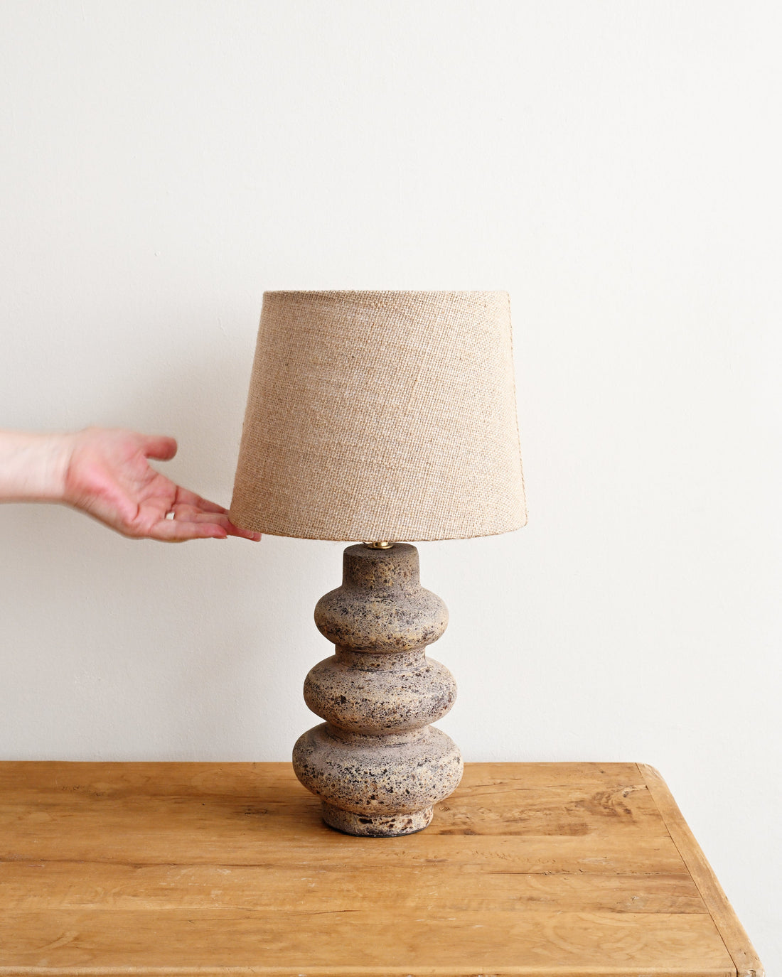 Table lamp with a textured base on a wooden table against a white wall
