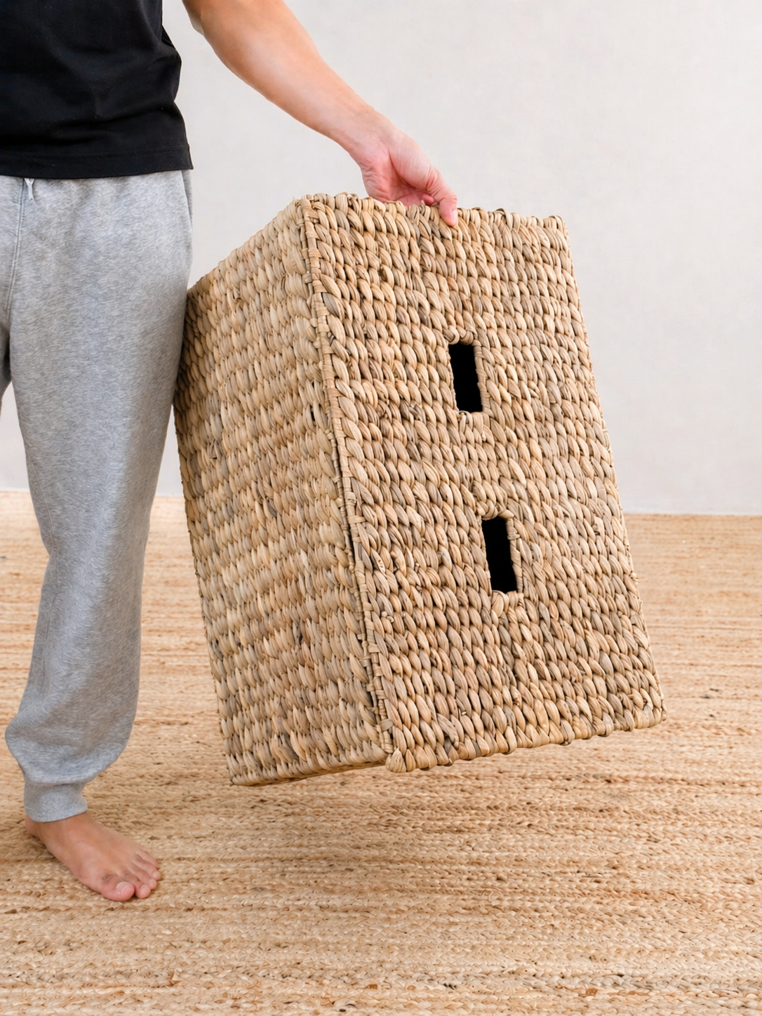 Person holding a woven basket on a wooden floor