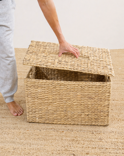 Person opening a woven storage basket on a wooden floor