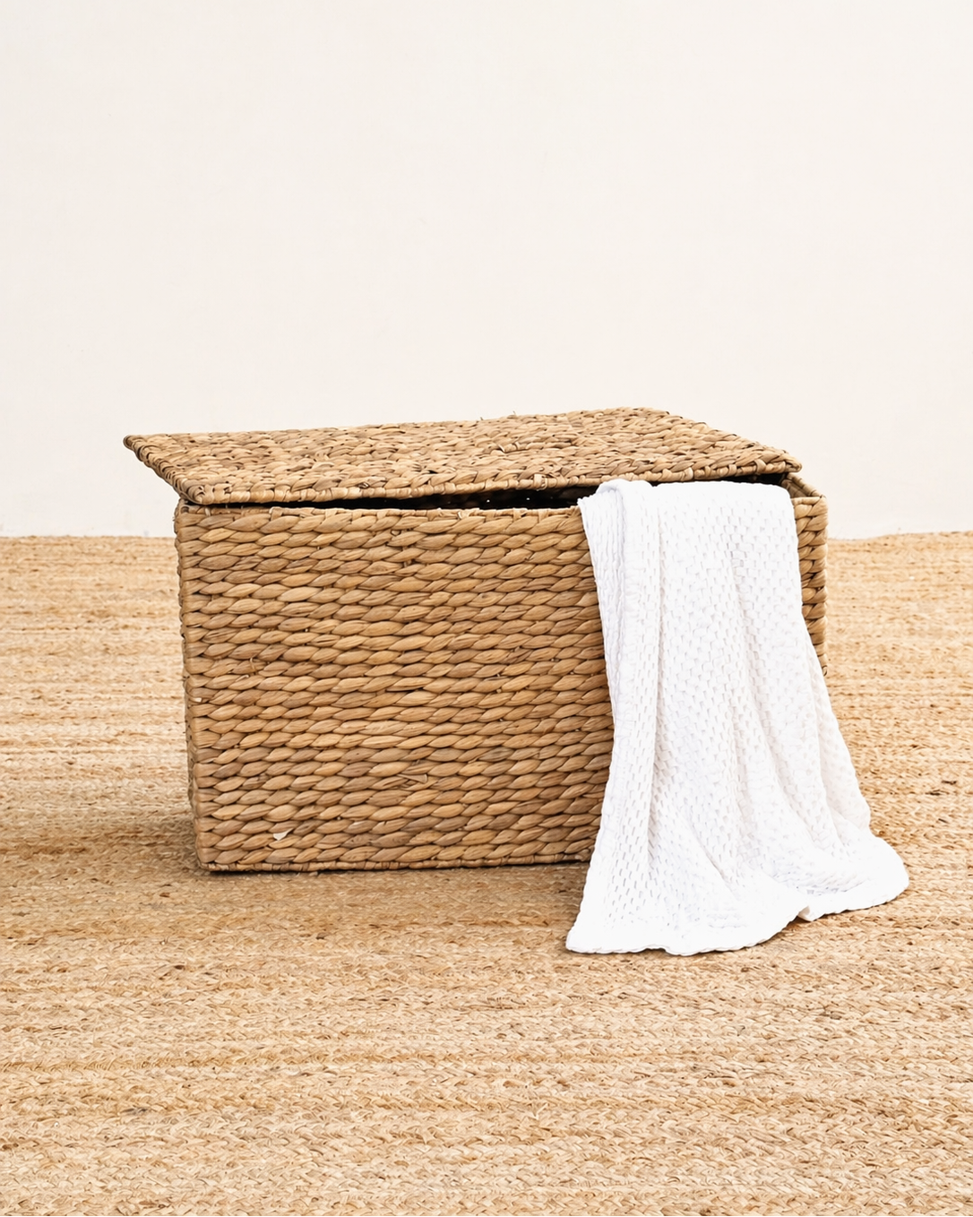 Woven storage basket with a white towel on a beige surface