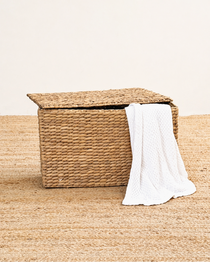 Woven storage basket with a white towel on a beige surface