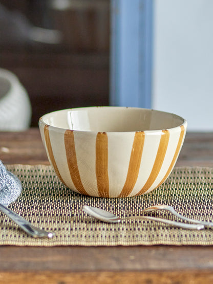 Wooden bowl with gold stripes on a woven placemat with cutlery