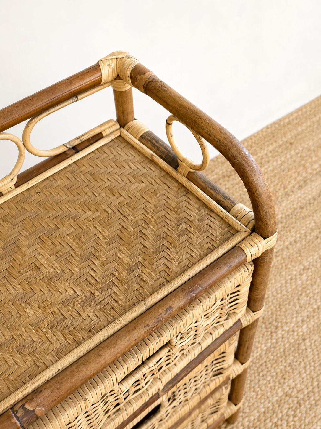 Wicker bar cart with wooden handles on a beige carpet