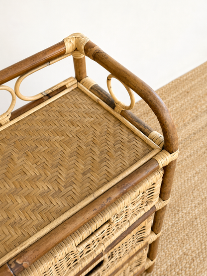 Wicker bar cart with wooden handles on a beige carpet